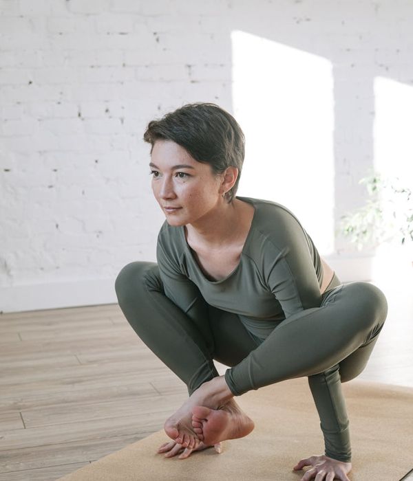 Woman performing a gentle yoga stretch in a bright, calm room.